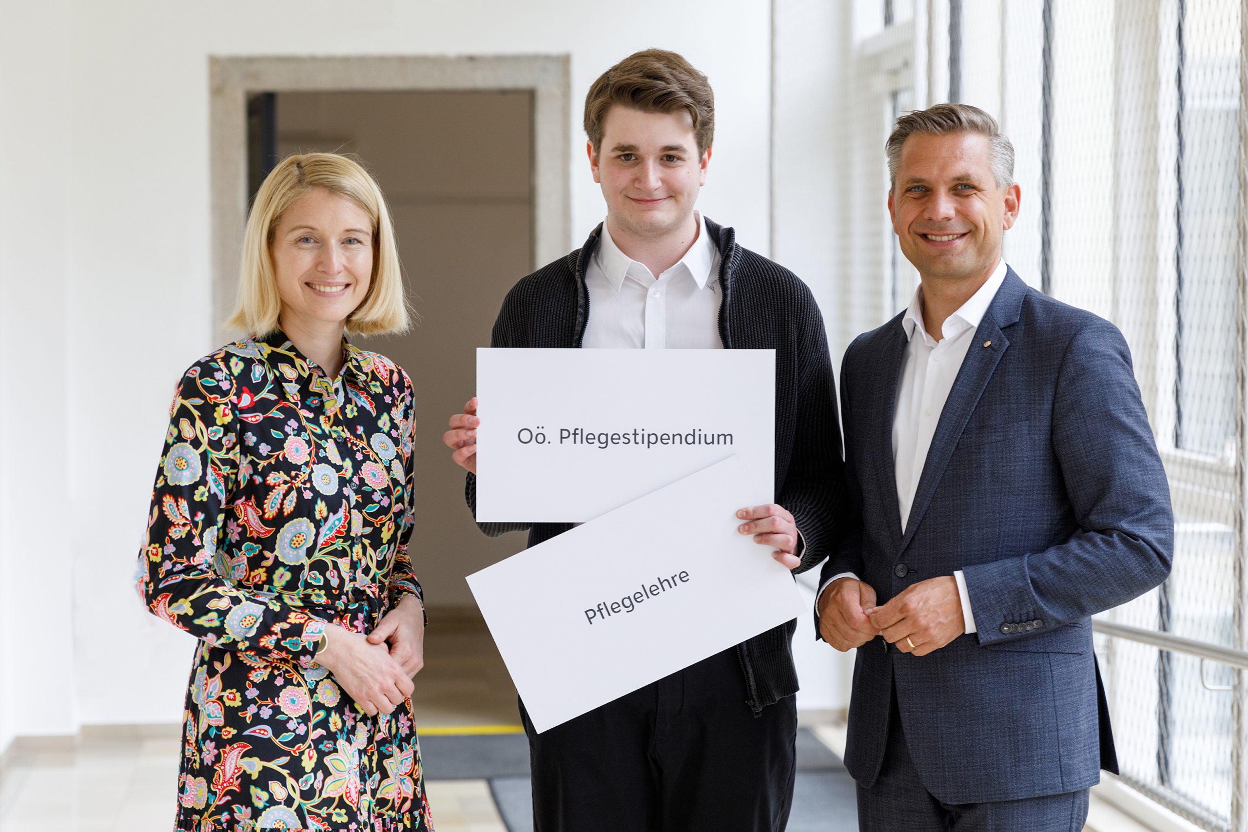 LH Stv Haberlander, Pascal Spatzek und LR Hattmansdorfer halten zwei Schulder mit den Begriffen "OÖ Pflegestipendium" und "Pflegelehre"