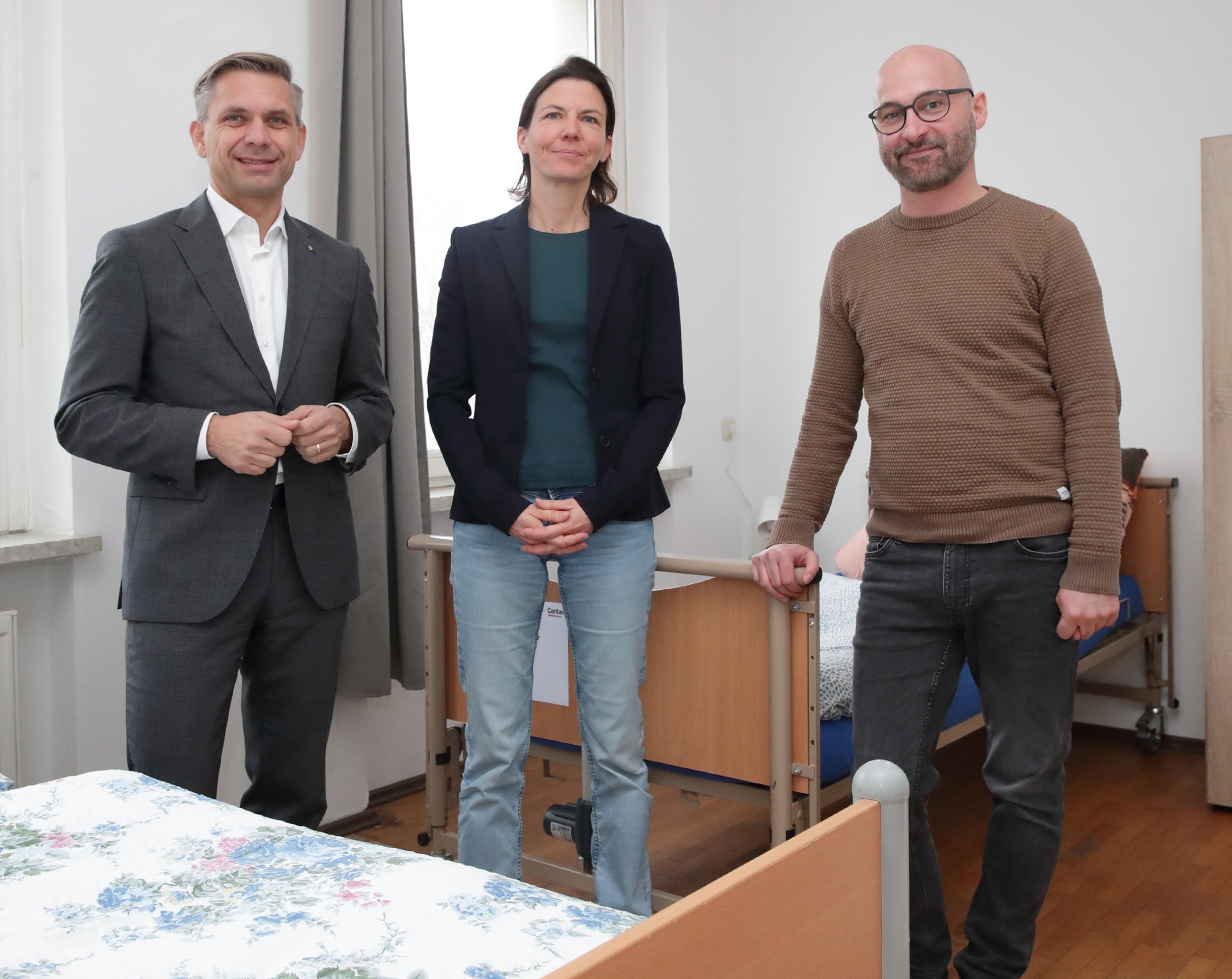 Landesrat Hattmannsdorfer, Caritas-Vorständin Marion Huber und Leiter Christian Koschka im neuen „Krankenzimmer“ der Caritas für wohnungslose Menschen.